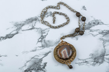 A pendant with onyx and filigree in vintage style on a marble background