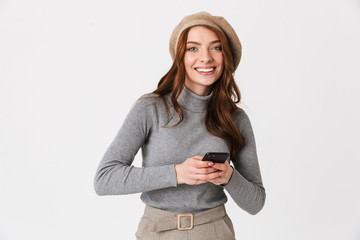 Photo of elegant woman 30s wearing hat smiling and holding cell phone