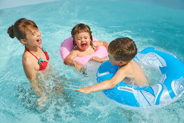 children in inflatable swimming circle playing in swimming pool