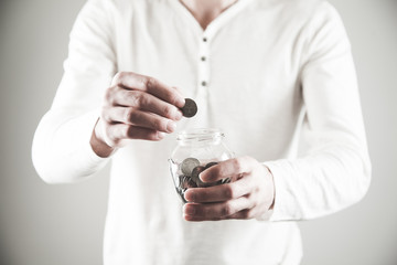 man hand holding coin with jar