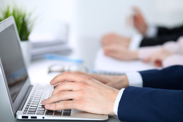 Group of business people working together in office. Man hands typing on laptop computer
