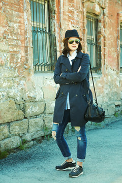 outdoor portrait of a stylish woman in raincoat, hat and sunglasses