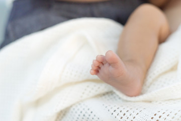 leg and foot of baby on white blanket with copy space for text