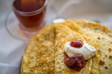 Russia, Severodvinsk, a stack of homemade Russian pancakes with sour cream and strawberry jam, selective focus
