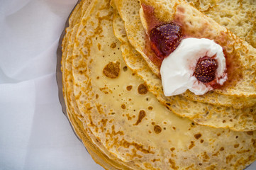 Russia, Severodvinsk, a stack of homemade Russian pancakes with sour cream and strawberry jam, flat lay
