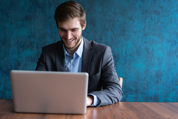 Happy young businessman using laptop at his office desk.