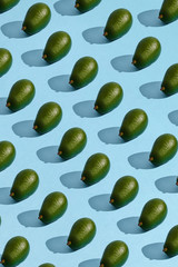 Colorful fruit pattern of fresh whole avocado arranged on blue pastel background