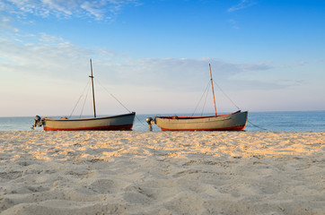 Fishing boats moored near the shore at sunset background