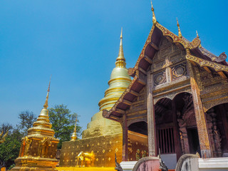 Naklejka premium Ancient wooden temple and gold pagoda with blue sky background