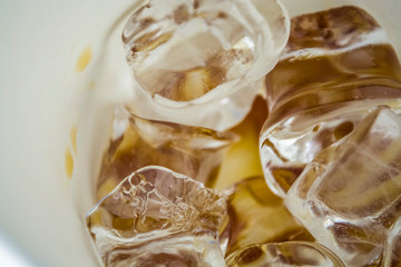 Cubes of large ice from a glass with strong coffee. Alternative Cold Brew drink. Play of color and patches of light. 
