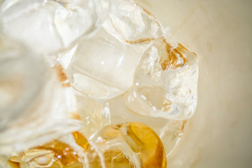 Cubes of large ice from a glass with strong coffee. Alternative Cold Brew drink. Play of color and patches of light. 