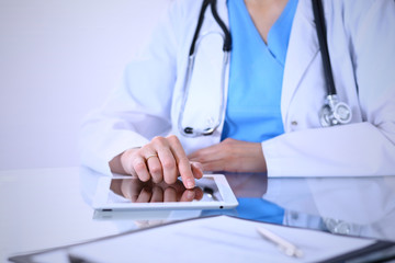 Woman doctor using tablet computer while standing straight in hospital office, closeup. Healthcare, insurance and medicine concept