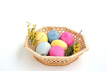 Fototapeta na wymiar Multi-colored Easter eggs in a wicker basket on a white background. Selective focus.