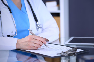 Female doctor filling up medical form on a clipboard, closeup. Healthcare, insurance and medicine concept