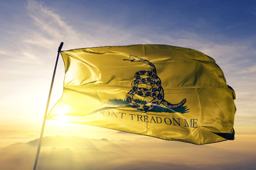 Gadsden flag waving on the top sunrise mist fog