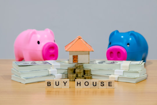 A piggy bank put on the stacking gold coins and blackboard house and clock on the vintage blue background, saving money for buy a new real estate or loan for planned investment in the future concept.
