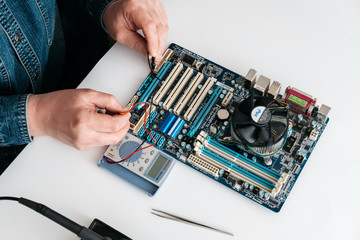 echnician using voltage meter for voltage measurement in computer mainboard. The concept of...