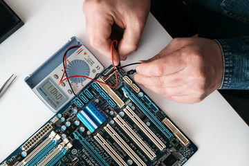 Technician using voltage meter for voltage measurement in computer mainboard. The concept of...