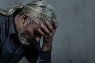 Sad man on dark background. Empty space for text