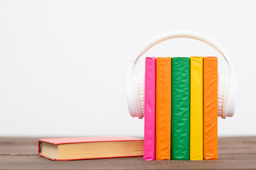Fototapeta na wymiar Multicolored books with white headphones on white background. Empty space for text