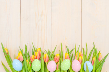 Tulips  and easter eggs over wooden background. Backdrop with empty space for text