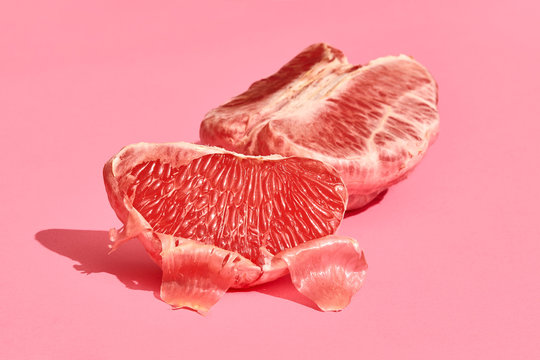 Close up high quality image of peeled slices of juicy grapefruit on a pink background