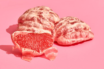 Close up high quality image of peeled slices of juicy grapefruit on a pink background