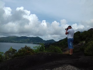 The man on the cliff taking pictures of the seascape