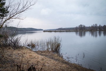 Deep calm river in the spring evening against a cloudy sky