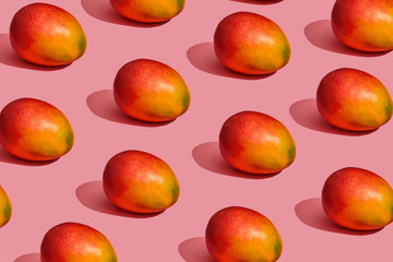 Pattern composition of a sweet tasty mango lying next to a pink background , top view
