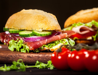 Fresh burgers on wooden table and dark background