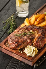 Fotobehang Ribeye steak with potatoes, onions and baked cherry tomatoes. Juicy steak with flavored butter © FoodAndPhoto
