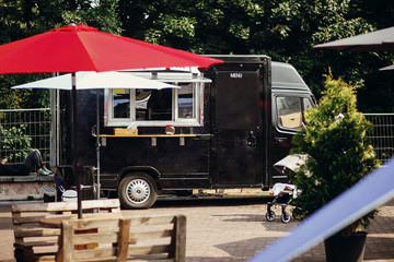 Food van truck. Stylish black mobile food truck with burgers and asian food at street food festival. Summer eating market in the city. Space for text, menu