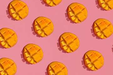 Colorful fruit pattern of fresh juicy cutted mango on coral pink background, top view