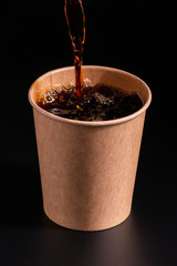 coffee pouring into disposable paper cup on a black background, takeaway coffee cup, moke up