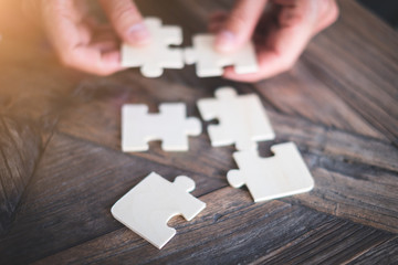 hands holding piece of jigsaw puzzle in office Business and team work concept