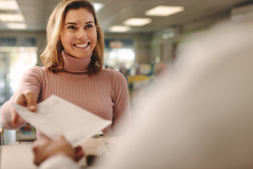 Female customer giving prescription to pharmacist