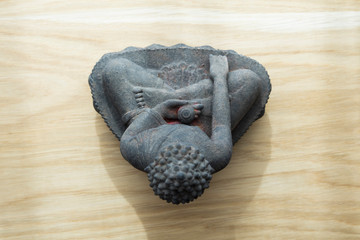 Statue or figurine of sitting black indian buddha on wooden floor from above