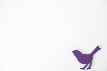 One little violet felt bird in front of white background
