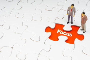 FOCUS inscription written on jigsaw puzzle and businessman miniature. Business and motivation concept