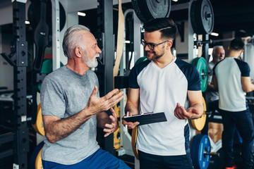 Fototapeta Senior man exercising in gym with his personal trainer. obraz