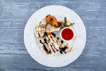 Fillet of a squid on a grill, is served with leek and tomato sauce