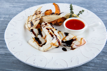 Kalmar on a grill with hot sauce and potatoes a share