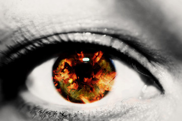 Double exposure of the closeup female eye and hot red coals from firewood in a fireplace