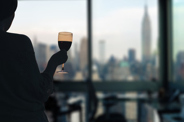 Female with glasse of red wine in the apartment with New York city view.