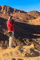 Fototapeta premium Young man taking a photos of mountain range Red Sea Hills in Arabian desert, Egypt