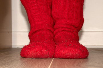 Red knitted socks of rough wool on the feet