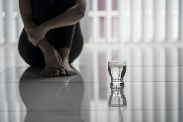 Lonely woman sitting with a glass of water