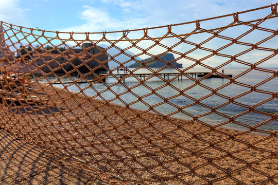 Fishing net dries in the sun and is blown by the wind, stretched against the backdrop of the sea coast.