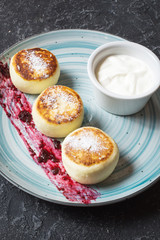 Cottage cheese pancakes on stone background. Syrniki with sour cream. Homemade food